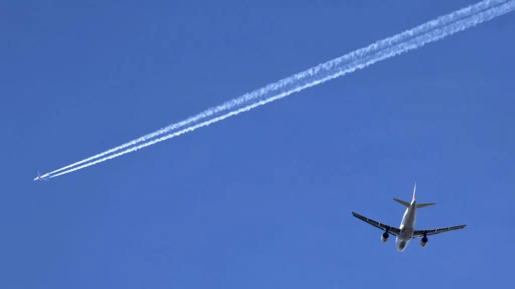 Two airplanes against clear blue sky with contrails